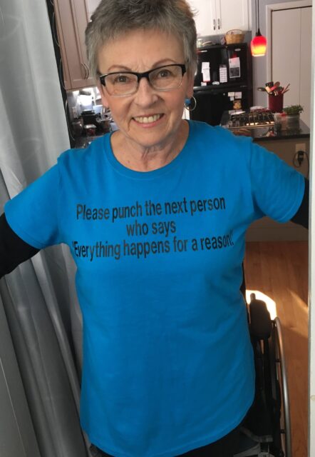 Phyllis Dodd poses in a t-shirt reading "Please punch the next person who says 'Everything happens for a reason.'